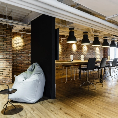 Modern office space with brick walls, wooden flooring, high ceilings, and a mix of seating options, perfect for open-floor plan office space rental.