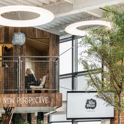 Unique treehouse-themed workspace in Warsaw Ochota with a person working on a laptop, surrounded by modern design elements and greenery, ideal for those seeking office space rental opportunities.