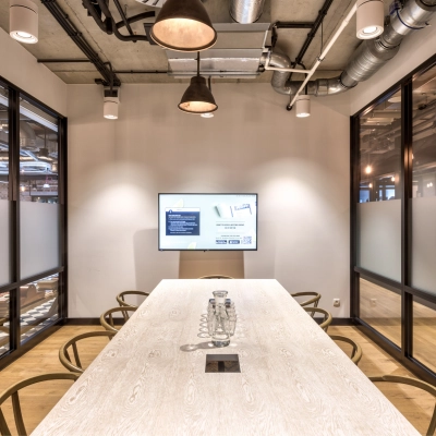 Modern office conference room at Koszykowa 61 in Warsaw Śródmieście, featuring a large table and a screen, ideal for meeting needs. Discover this office space rental opportunity for collaboration.