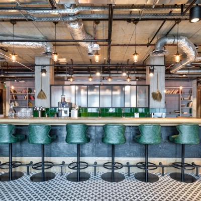 Modern office space at Koszykowa 61 in Warsaw Śródmieście featuring a chic bar area with green stools and industrial design elements, ideal for office space rental.