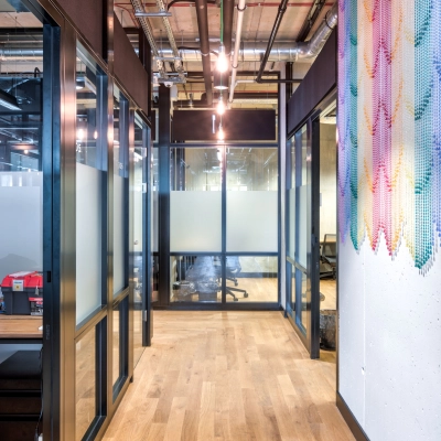 A bright, modern office hallway with glass partitions and a colorful wall mural at Koszykowa 65, perfect for office space rental in Warsaw Śródmieście.