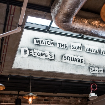 Interior office space at Koszykowa 65, Warsaw Śródmieście featuring industrial design elements and a skylight with a motivational quote. Ideal office to rent for creative thinkers.