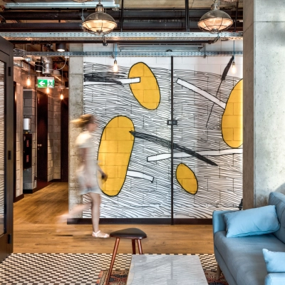 Furnished office space at Koszykowa 65 in Warsaw Śródmieście with modern decor and a casual seating area. A person is walking by, suggesting an active business environment.