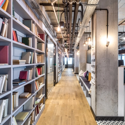 Bright office space to rent at Koszykowa 65, Warsaw Śródmieście, featuring bookshelves, a wooden floor, and modern lighting for an inviting atmosphere.