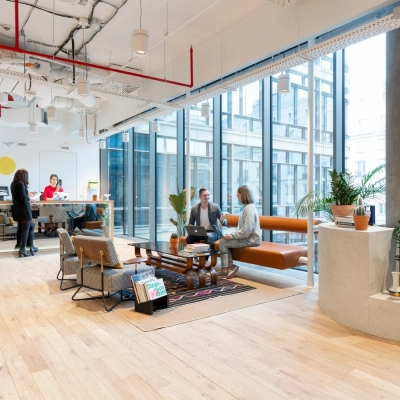 Modern office space at Krucza 50, Warsaw Śródmieście, featuring open seating areas with people engaged in conversation and light work. Ideal for office space rental.