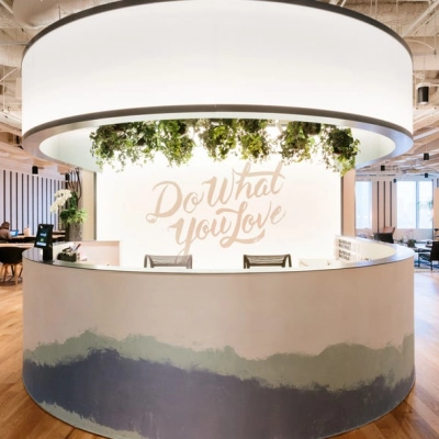 Modern office space rental at Grzybowska 60, Warsaw Wola featuring a circular reception desk with greenery and motivational signage.