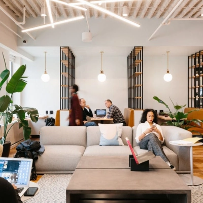 Modern office space at Grzybowska 60 in Warsaw Wola, featuring a comfortable lounge with people engaged in business tasks. Ideal for anyone looking to rent office space.