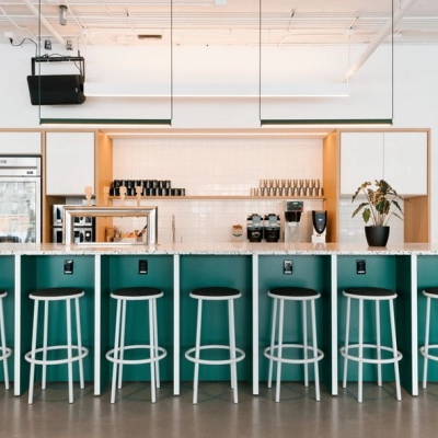 A modern, furnished office space with a long counter and stools, located at Rondo Daszyńskiego 2 in Warsaw Wola, available for rent office space.