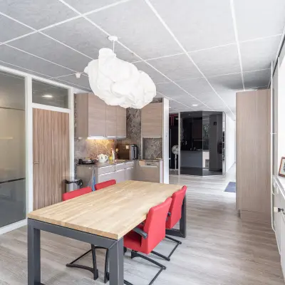 Bright office kitchen space with modern wooden tables and red chairs available for office space rental at Molenweer 2, Wateringen.