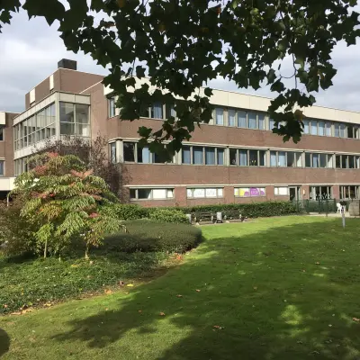 Exterior view of an office building at Houttuinlaan 4 in Woerden, surrounded by green lawns and trees, ideal for office space rental.