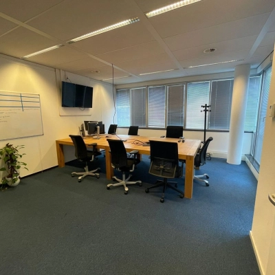 Modern conference room at Baron de Coubertinlaan 35, Zoetermeer, featuring a large wooden table, office chairs, a whiteboard, and a flat-screen TV, ideal for office space rental.