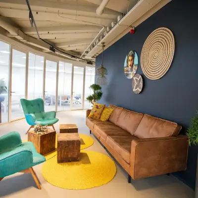 Inviting lounge area in an office with a brown sofa, two teal chairs, and decorative elements on the wall, located at Boerhaavelaan 40, Zoetermeer, offering office space rental options.