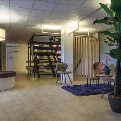Modern office space lounge at Bredewater 26, Zoetermeer, featuring a chic waiting area with stylish furniture and plants, ideal for rent. Perfect for welcoming clients or informal meetings in a professional setting.