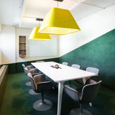 Bright conference room with a large white table, surrounded by comfortable chairs and modern lighting, available for office space rental at Talacker 41, Zürich Center.