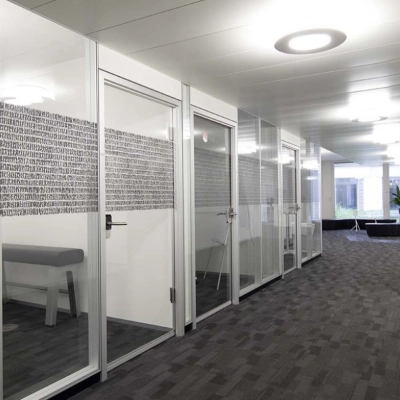 Modern office space for rent at Europaallee 41 in Zürich Mitte, featuring glass-walled meeting rooms and a well-lit hallway.