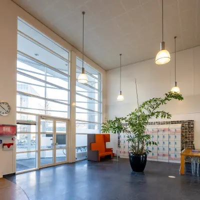 Bright and open office entrance with high ceilings, large windows, and a seating area, ideal for an inviting office space rental.
