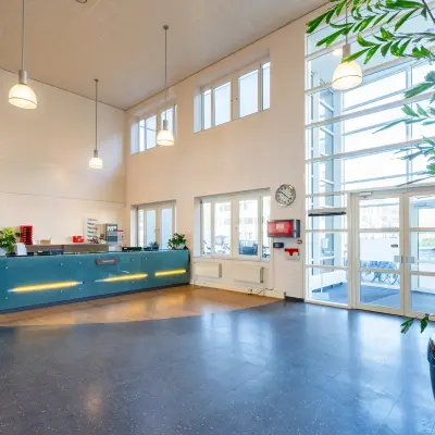 Spacious office entrance at Dokter van Deenweg 1, Zwolle, featuring a reception desk next to large windows with natural light, perfect for office space rental.