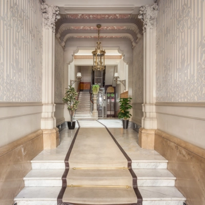 Entrada elegante y señorial para alquilar una oficina en Barcelona Eixample, Rambla de Catalunya 125, con suelo de mármol y detalles ornamentales en las paredes.