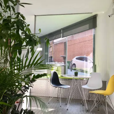 Sala de recepción en Carrer Albigesos 25-27, Barcelona Gràcia, con sillas modernas y una ventana amplia, ideal para quienes buscan alquilar una oficina con luz natural.