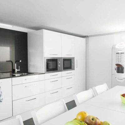 Cocina moderna y luminosa perfecta para alquilar una oficina en Carrer de L'Escorial 180, Barcelona Gràcia, con mesa blanca y electrodomésticos.