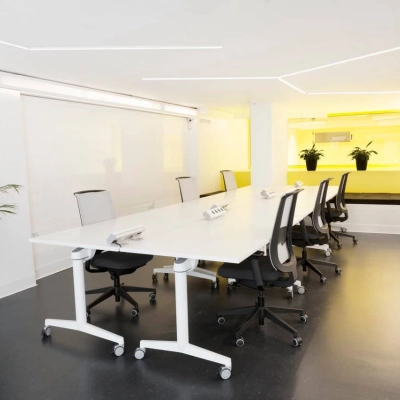 Sala de reuniones moderna con mesa blanca y sillas negras en alquiler de oficinas en Carrer de L'Escorial 180, Barcelona Gràcia.