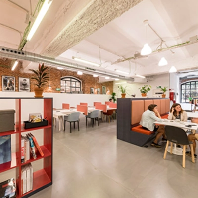 Espacio de trabajo compartido con mesas y sillas en alquiler de oficinas en Manzanares 4, Madrid Centro, con personas colaborando en proyectos.