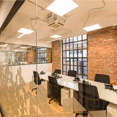 Espacio de alquiler de oficinas en Manzanares 4, Madrid Centro, con mesas y sillas modernas en un entorno luminoso con paredes de ladrillo visto.