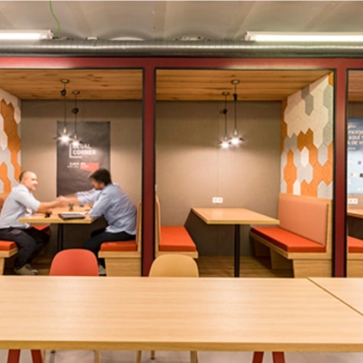 Oficinas en Manzanares 4, Madrid Centro, con espacios compartidos modernos para alquilar. Dos personas colaboran en un área de trabajo con decoración cálida y contemporánea.