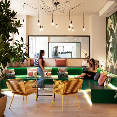 Luminosa sala de espera en alquiler de oficinas en Paseo Imperial 14, Madrid Centro, con sofás verdes, sillas amarillas y decoración moderna.