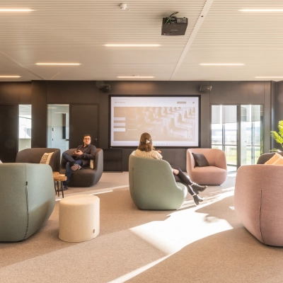 Moderne kantoorruimte op Korte Keppestraat 19 in Aalst met comfortabele zitmeubels en een groot presentatiescherm. Mensen zijn bezig met werkbesprekingen in deze lichte en uitnodigende omgeving.