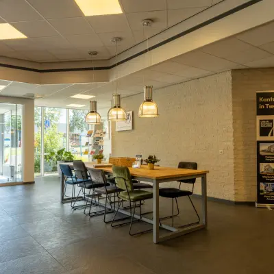 Inloop van een kantoorpand op Bedrijvenpark Twente 305 in Almelo met tafel en stoelen, geschikt voor huur van kantoorruimte.