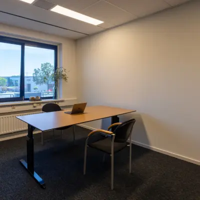 Kantoorruimte te huur in Almelo, gelegen op Bedrijvenpark Twente 305 met een eenvoudig bureau en stoelen, geschikt voor één of twee personen met uitzicht op bedrijventerrein.