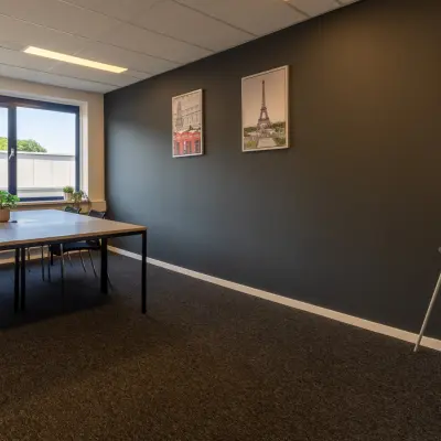 Ruime kantoorruimte te huur in Almelo met grote tafel en stoelen, voorzien van natuurlijk licht en inspirerende wanddecoratie.