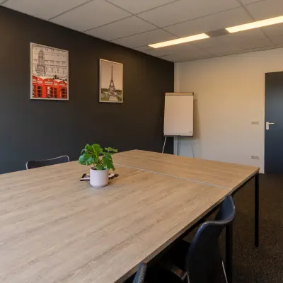 Kantoorruimte huren op Bedrijvenpark Twente 305 in Almelo met een moderne vergaderruimte, gedecoreerde muren en een houten tafel met stoelen.
