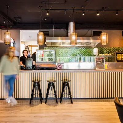 Moderne kantoorruimte in Almere Stad bij Markerkant 1310, met een stijlvolle gemeubileerde lounge met industrieel interieur, ideaal voor pauzes. Personeel serveert koffie aan de bar.