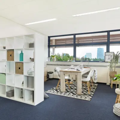 Lichte kantoorruimte met grote ramen en zicht op Almere Stad, voorzien van vergadertafel en decoratieve elementen. Geschikt voor werkruimte of vergaderruimte voor wie kantoorruimte wil huren.