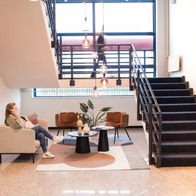 Moderne kantoren te huur op Markerkant 1310 in Almere Stad; lichte entree met comfortabele meubels en een stijlvolle trap.