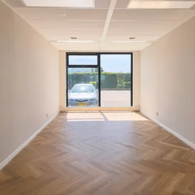 Kantoorruimte te huur op Veluwezoom 15 in Almere Stad met zicht op de parkeerplaats, voorzien van visgraat vloer en grote ramen voor natuurlijk licht.