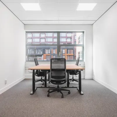 Heldere kantoorruimte met grote ramen en een tafel met stoelen in kantoorpand op Veluwezoom 15, Almere Stad, ideaal voor kantoorruimte huren.