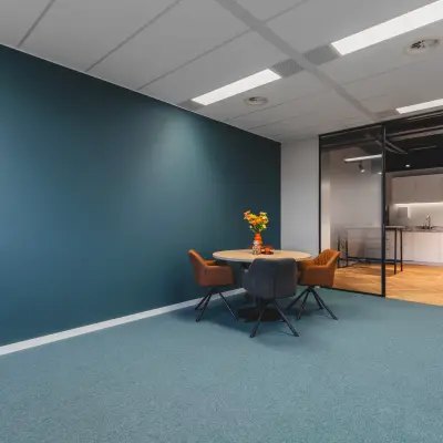 Moderne kantoorruimte te huur op Veluwezoom 15 in Almere Stad, met een tafel en stoelen. Het kantoor heeft een strak, minimalistisch design en is ideaal voor vergaderingen of werkontmoetingen.