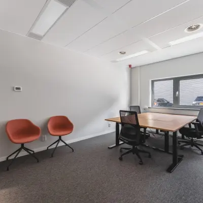Kantoorruimte huren aan Veluwezoom 15 in Almere Stad met strak bureau en moderne stoelen, gelegen in een lichte ruimte met groot raam.