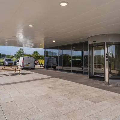 Entree van Veluwezoom 15 in Almere Stad met een draaideur en zitgelegenheid buiten. Ideaal voor bedrijven die op zoek zijn naar kantoorruimte om te huren.