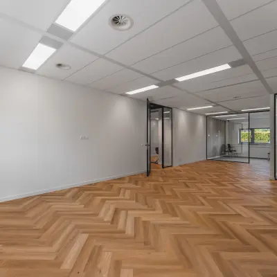 Moderne kantoorruimte op Veluwezoom 15 in Almere Stad met houten vloer en glazen tussenwanden. Ideaal om te huren voor een professionele werkomgeving.