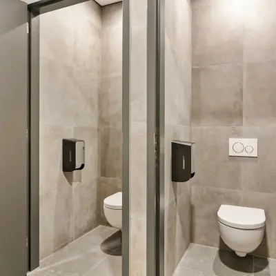 Twee moderne toiletcabines in een kantoorpand op Astronaut 28 in Amersfoort Calveen met grijze tegels.