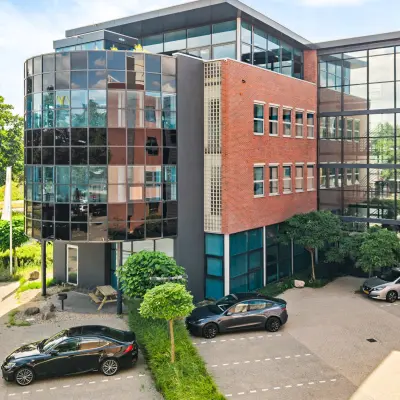 Modern kantoorpand met glazen en bakstenen gevel op Maanlander 43, Amersfoort Calveen, met meerdere geparkeerde auto's ervoor. Ideale optie voor kantoorruimte huren.