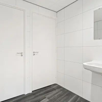 Wit betegelde toiletruimte in kantoorpand met wastafel en spiegel op Maanlander 43, Amersfoort Calveen. Kantoorruimte huren in een nette omgeving.