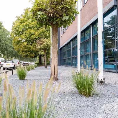 Buitenzijde van een modern kantoorpand op Maanlander 43 in Amersfoort Calveen, met goed onderhouden groen en grote glazen ramen. Geschikt om een kantoorruimte te huren.