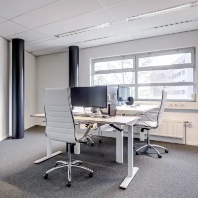 Modern ingerichte kantoorruimte met grote ramen die natuurlijk licht binnenlaten, gelegen in het kantoorpand op Maanlander 47, Amersfoort Calveen. Twee werkplekken zijn uitgerust met bureaustoelen en computers.