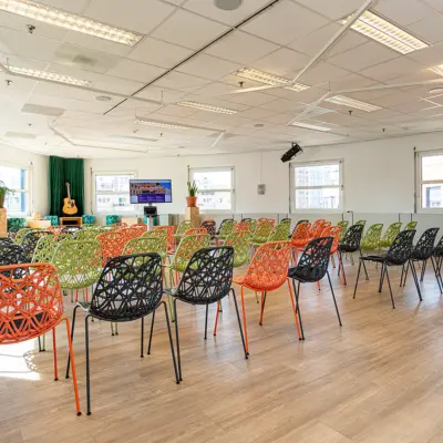 Ruime, lichte kantoorpand met kleurrijke stoelen en een podium voor presentaties, gelegen bij Amersfoort Centraal Station. Ideale plek om kantoorruimte te huren met flexibele indeling.