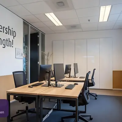 Moderne kantoorruimte met vier werkplekken bij Amersfoort Centraal Station, ideaal om te huren voor kleine teams. Voorzien van strakke bureaus en computers, met natuurlijk lichtinval door grote ramen.